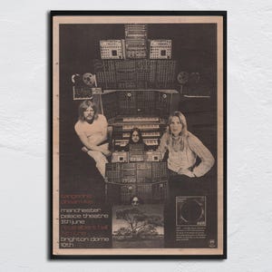 May include: Black and white framed poster featuring a band with long hair, surrounded by electronic music equipment. The poster includes the band's name, tour dates, and venue locations. The poster has a vintage aesthetic.