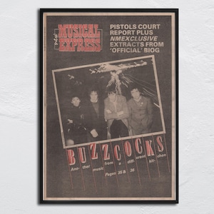 Peut inclure: Une affiche vintage encadrée du Musical Express avec le groupe Buzzcocks. L'affiche a un cadre noir et un fond sépia. Le texte comprend "Pistols Court Report" et "Extraits de 'Official' Biog."