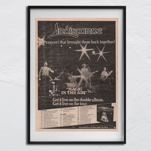 May include: A black and white photo of the band Indisfarne. The band members are standing on a stage with microphones and instruments. The text "The concert that brought them back together!" is at the top of the image. The text "MAGIC IN THE AIR" is in the middle of the image. The text "Get it live on the double album. Get it live on the tour." is at the bottom of the image. The text "Recorded live at Newcastle City Hall" is at the bottom of the image.