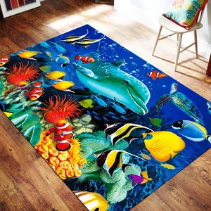 Puede incluir: Una alfombra colorida con un fondo azul que presenta un delfín, tortugas marinas y varios peces tropicales nadando entre arrecifes de coral. La alfombra es perfecta para agregar un toque de océano a cualquier habitación.