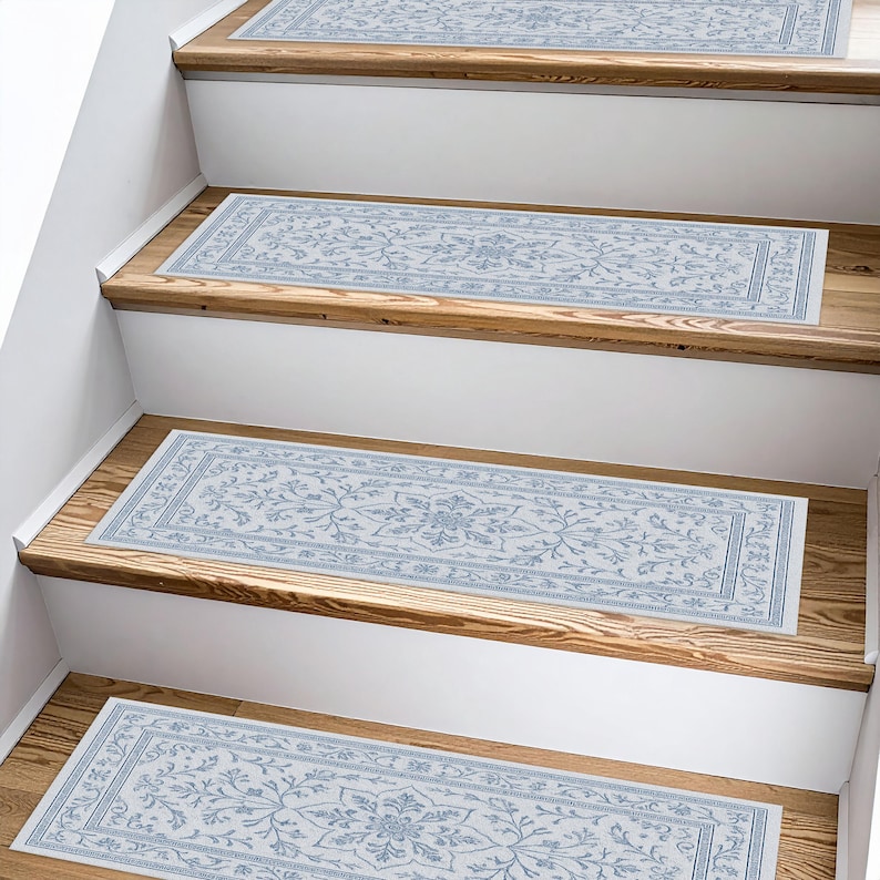 K&ouml;nnte beinhalten: Mehrere hellblaue und wei&szlig;e Treppenl&auml;ufer mit floralem Muster. Die rechteckigen L&auml;ufer liegen auf Holztreppen. Das Design zeigt ein zentrales Medaillon und Bord&uuml;rendetails, die der Treppe eine dekorative Note verleihen.
