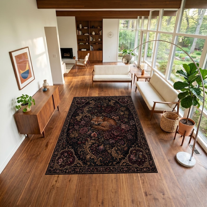 Puede incluir: Una alfombra rectangular con fondo oscuro que presenta una ilustraci&oacute;n central de un zorro durmiendo rodeado de intrincados patrones florales y bot&aacute;nicos en tonos rojo intenso, dorado y marr&oacute;n, colocada sobre un suelo de madera en una sala.