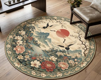 Puede incluir: Una alfombra redonda con una ilustración detallada de dos grullas en vuelo, un gran sol rojo, montañas estilizadas y flores en tonos rojos, blancos y verdes. La alfombra tiene un borde decorativo con un patrón floral repetitivo.