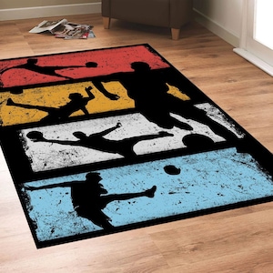 May include: A black and white rug with a retro design featuring silhouettes of soccer players kicking a ball. The rug has a distressed look with a faded background in shades of red, yellow, blue, and white.