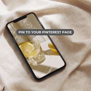 May include: A smartphone displaying a photo of a glass of water with lemon slices on a white surface. The text "PIN TO YOUR PINTEREST PAGE" is displayed on the screen.