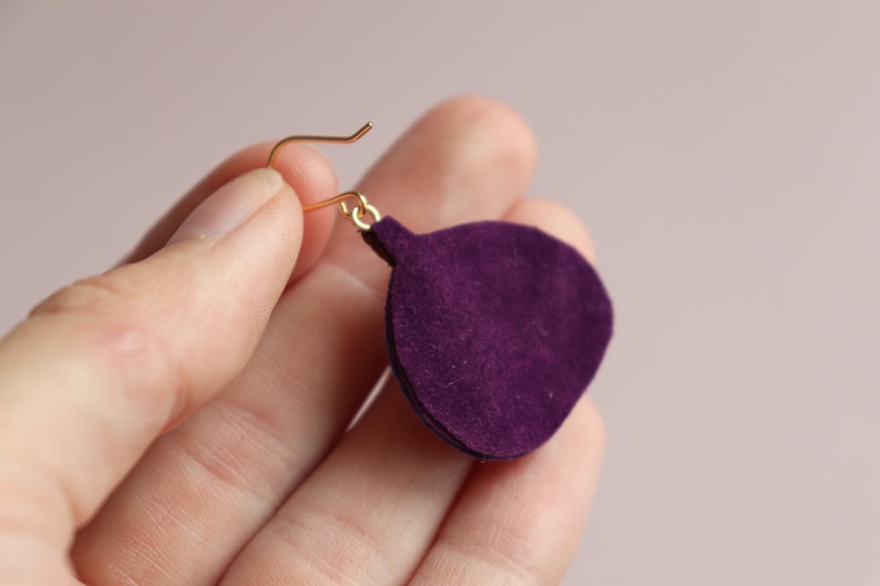May include: Purple suede earring with a gold hook.