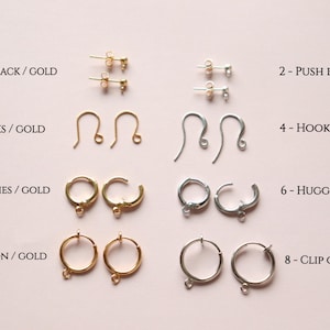 May include: Eight pairs of earring findings in gold and silver. The findings include push backs, hooks, huggies, and clip ons.
