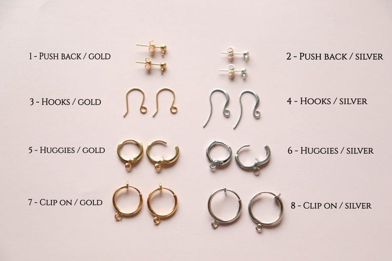 May include: Eight pairs of earring findings in gold and silver. The findings include push backs, hooks, huggies, and clip ons.