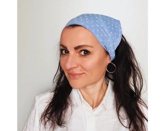May include: A woman with long dark hair is wearing a light blue bandana with white polka dots. The bandana is tied around her head and covers her forehead. She is wearing a white button-down shirt.