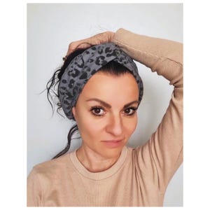 Puede incluir: Una diadema de leopardo gris y negro con un diseño anudado.