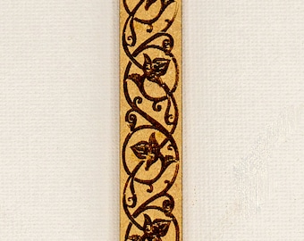 May include: A close-up of a decorative wooden border with a repeating pattern of stylised flowers and vines. The border is a light brown colour and the design is dark brown.