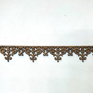 May include: A decorative wooden trim piece with an ornate, repeating scrollwork design. The trim is a warm brown color and features a scalloped bottom edge. Perfect for adding a vintage touch to home decor projects.