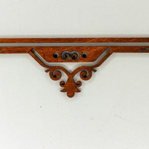 以下が含まれることがあります： 濃い茶色の仕上げが施された装飾的な木製ブラケット。ブラケットは、渦巻き模様や中央の花柄など、複雑な切り抜きデザインが特徴です。 全体的な形状は、湾曲した端を持つ長方形です。