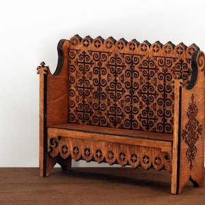 May include: A wooden bench with intricate carvings on the back and sides. The bench is made of light brown wood and has a dark brown stain. The back of the bench is decorated with a repeating pattern of swirls and circles.