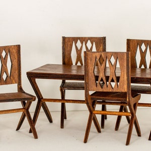 May include: A miniature wooden dining set with a table and four chairs. The chairs have a geometric diamond pattern cut out of the back.