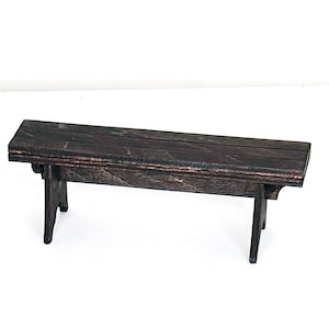May include: A dark brown wooden bench with a simple design. The bench has a rectangular top and two angled legs on each side.