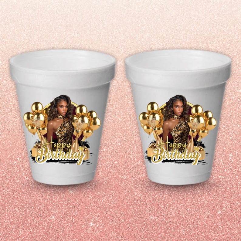 May include: Two white foam cups with a printed design. Each cup features a woman in a leopard print top, gold balloons, and the words "Happy Birthday" in gold script. The cups are on a pink glitter background.
