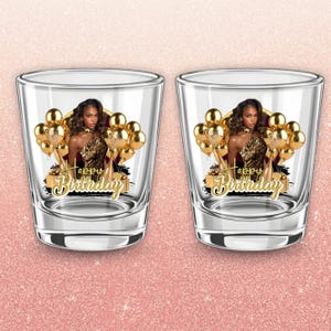 May include: Two clear shot glasses with a gold and black design. Each glass features a woman in a leopard print dress, gold balloons, and the words "Happy Birthday" in gold script.