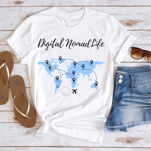 May include: White t-shirt with a blue world map and the text "Digital Nomad Life". The map has black pins and a black airplane.