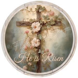 May include: Round decorative sign featuring a wooden cross adorned with climbing vines, pink and white flowers, and the text "He is Risen." The sign has a light wood grain border and a soft, pastel background.