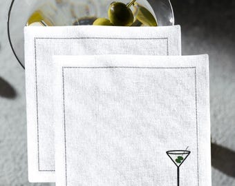 May include: Two white linen cocktail napkins with a black embroidered martini glass design. The napkins have a subtle gray border.