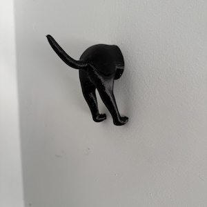 May include: Black wall-mounted hook shaped like a dog sticking its head through a hole in the wall.