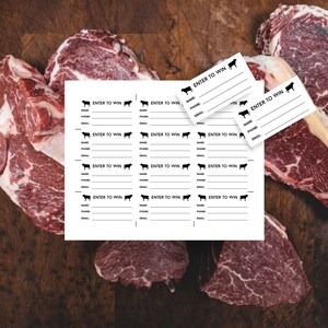 May include: A white sheet of paper with multiple entry to win forms. Each form has a black cow silhouette, a line for name, phone, and email. The paper is on a wooden surface with three pieces of raw meat.