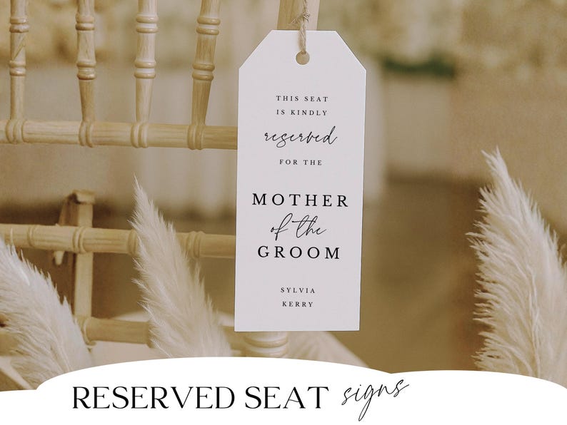 May include: A white reserved seat sign for the Mother of the Groom, hanging from a wooden chair. The sign includes the text "This seat is kindly reserved for the Mother of the Groom" and the names Sylvia Kerry.
