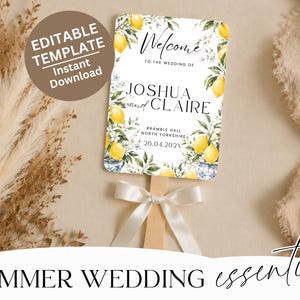 May include: A rectangular wedding hand fan featuring a white background with yellow lemon illustrations, green leaves, and blue and white patterned vases. The text reads Welcome to the wedding of Joshua and Claire, Bramble Hall, North Yorkshire, 26.04.202X, with a white ribbon tied to the wooden handle.