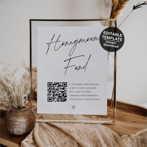 Pode incluir: Um cartaz branco com texto preto que diz "Honeymoon Fund". Um código QR está no centro do cartaz. O texto abaixo do código QR diz "Se você estava pensando em dar um presente para nos ajudar em nosso caminho, um presente em dinheiro para nossa lua de mel realmente faria nosso dia." Um símbolo de coração está abaixo do texto. O cartaz está em uma moldura prateada e está sentado em uma mesa.