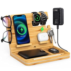 May include: A wooden charging station with slots for a phone, smartwatch, and earbuds. It also has a space for a wallet and a small compartment for keys. The station is made of light brown wood and has a white trim.