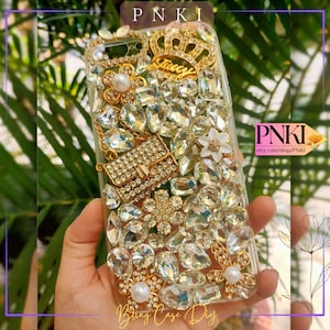 May include: Clear phone case bedazzled with large, sparkling rhinestones and gold accents. Features a gold crown with "Juicy" text, a miniature handbag, and floral embellishments. The words "Bling Case Diy" are at the bottom.