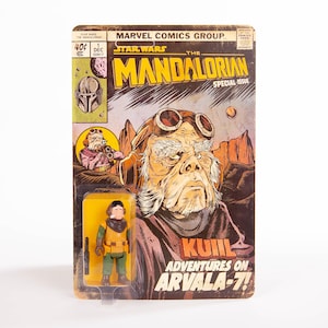 May include: A vintage Star Wars comic book featuring "The Mandalorian" and a Kuill action figure. The comic cover has a brown and yellow color scheme with the text "KUIIL Adventures on Arvala-7!" and the Marvel Comics Group logo.
