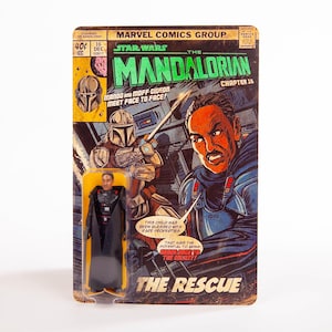 May include: A vintage-style Star Wars: The Mandalorian comic book cover with a Moff Gideon action figure. The comic features illustrations of Mando and Moff Gideon, with text that reads "The Rescue". The action figure is in a clear plastic case.