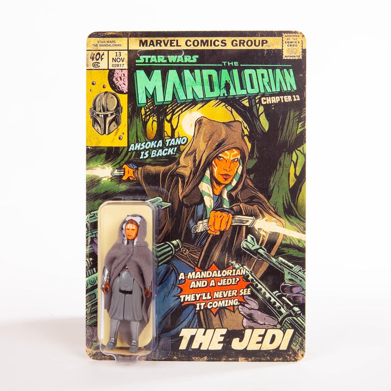 Puede incluir: Una figura de acci&oacute;n vintage de Star Wars de Ahsoka Tano, empaquetada en una tarjeta de respaldo estilo c&oacute;mic. La tarjeta presenta ilustraciones de la serie "The Mandalorian", con el texto "Ahsoka Tano is Back!" y "The Jedi."