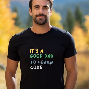 Könnte beinhalten: Ein schwarzes T-Shirt mit dem Text "It's a good day to learn code" in bunten Buchstaben.