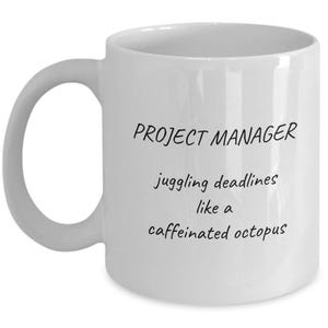 May include: White ceramic mug with a curved handle. The mug features the text "PROJECT MANAGER" above the phrase "juggling deadlines like a caffeinated octopus" in black script. A humorous gift for project managers.