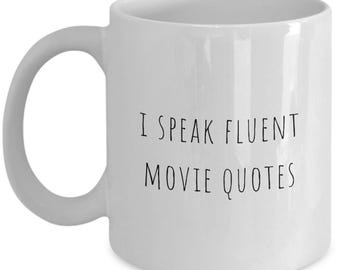 May include: White ceramic mug with a curved handle. The mug features the text "I SPEAK FLUENT MOVIE QUOTES" in black, centered on the front. The mug is designed for hot beverages.