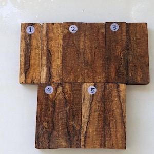 Può includere: Cinque pezzi di legno con diverse venature, numerati da 1 a 5. Il legno è di colore marrone scuro con striature marrone chiaro.