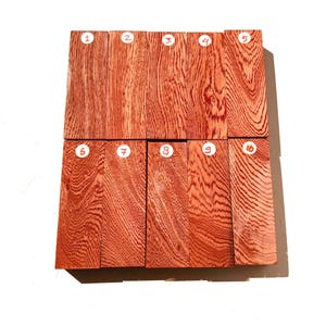 May include: Ten pieces of red wood with a distinctive grain pattern, numbered 1 through 10 in white circles. The wood has a reddish-brown hue with darker, swirling grain lines. The pieces are arranged in a rectangular shape.