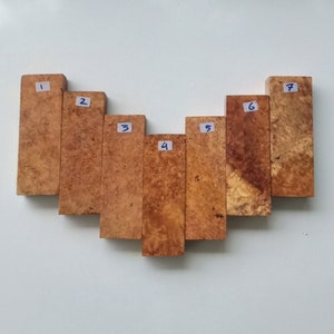 May include: Seven wooden blocks arranged in a heart shape, each block is numbered 1 through 7. The blocks are a light brown colour with a darker brown marbling pattern.
