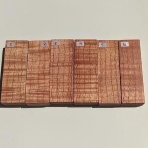 May include: Six wooden blocks, numbered 1 through 6, with a wood grain pattern. The blocks are arranged in a row from left to right.