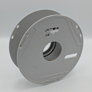 May include: A gray spool of ELEGOO PLA Basic Black filament for 3D printing. The spool has a large central hole and a label with the text "PLA Basic Black" and temperature range 190°C-230°C.