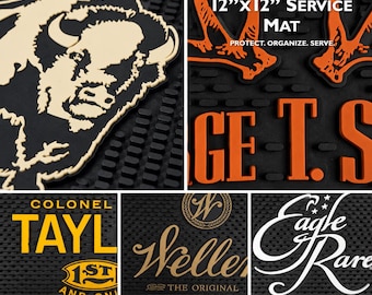 Puede incluir: Una alfombrilla de servicio de goma negra de 30,48 cm por 30,48 cm, con diseños en relieve que incluyen una cabeza de búfalo, texto naranja y varios logotipos de marcas como Colonel Taylor, Weller y Eagle Rare sobre una superficie texturizada.