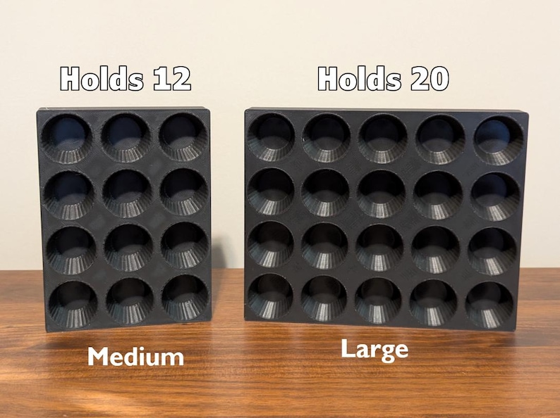 K&ouml;nnte beinhalten: Zwei schwarze Silikon-Muffinbackformen. Die Form links ist mit "Holds 12" und "Medium" beschriftet. Die Form rechts ist mit "Holds 20" und "Large" beschriftet.