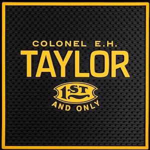 Pu&ograve; includere: Tappetino da bar nero con bordo giallo e la scritta "COLONEL E.H. TAYLOR" in grassetto giallo. Sotto il nome c'&egrave; un emblema giallo che recita "1ST AND ONLY". Il tappetino ha una superficie strutturata.