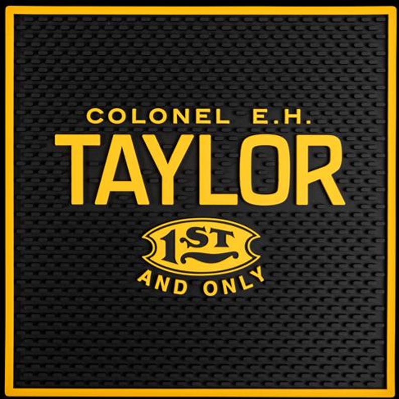Pu&ograve; includere: Tappetino da bar nero con bordo giallo e la scritta "COLONEL E.H. TAYLOR" in grassetto giallo. Sotto il nome c'&egrave; un emblema giallo che recita "1ST AND ONLY". Il tappetino ha una superficie strutturata.