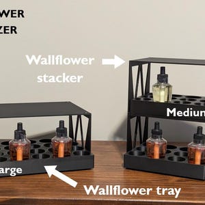 K&ouml;nnte beinhalten: Schwarzer Wand-Duft&ouml;l-Organizer aus Metall mit zwei Ebenen. Die obere Ebene ist mit "Medium" und die untere Ebene mit "Large" beschriftet.