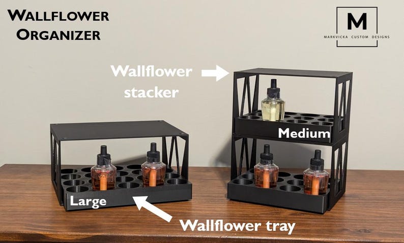 K&ouml;nnte beinhalten: Schwarzer Wand-Duft&ouml;l-Organizer aus Metall mit zwei Ebenen. Die obere Ebene ist mit "Medium" und die untere Ebene mit "Large" beschriftet.