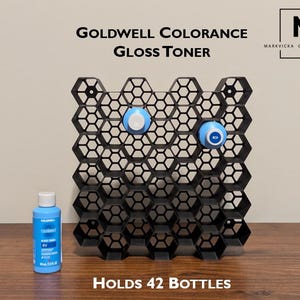 May include: Black honeycomb-shaped shelf designed to hold 42 bottles of hair toner. The shelf is made of plastic and has a modern design. The text "GOLDWELL COLORANCE GLOSS TONER" is printed above the shelf. The text "HOLDS 42 BOTTLES" is printed below the shelf.